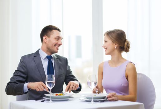 restaurant, couple and holiday concept - smiling couple eating appetizers at restaurant