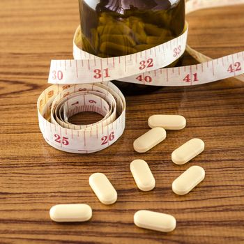 pills and measuring tape concept diet with drug