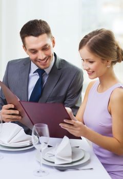 restaurant, couple and holiday concept - smiling couple with menu at restaurant