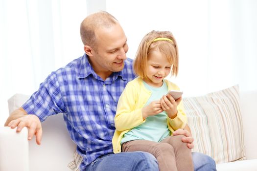 family, children, parenthood, technology and internet concept - happy father and daughter with smartphone at home