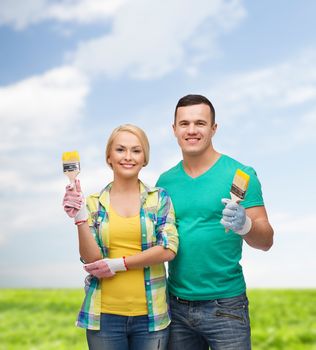 repair, construction and maintenance concept - smiling couple with paintbrush