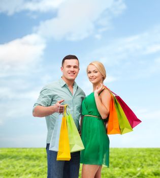 happiness, shopping and couple concept - smiling couple with shopping bags