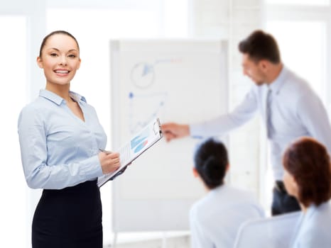 business and education concept - friendly young smiling businesswoman with clipboard and pen