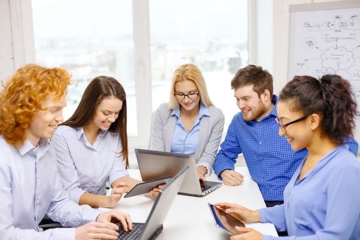 business, office and startup concept - smiling creative team with table pc and laptop computers working in office