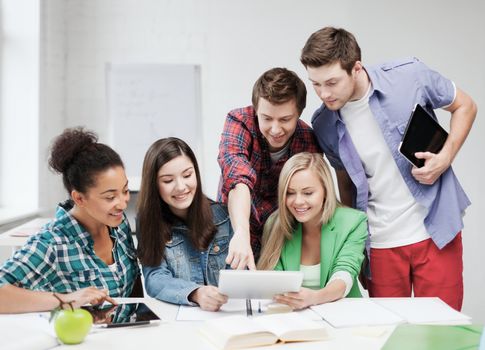 education concept - smiling students looking at tablet pc at school