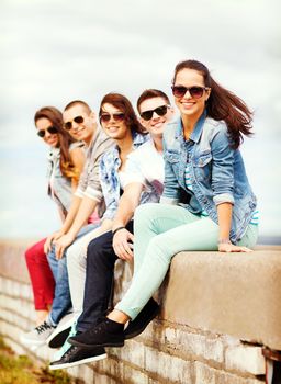 summer holidays and teenage concept - group of teenagers hanging out outside