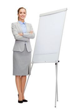 business, education and office concept - smiling businesswoman standing next to flip board