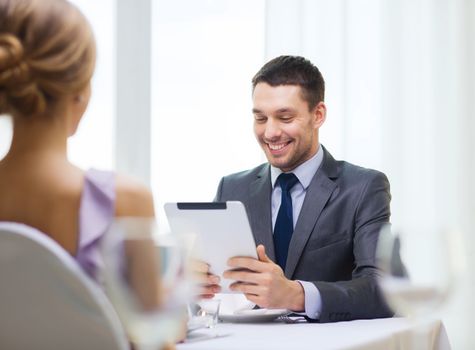 restaurant, couple, technology and holiday concept - smiling man looking at menu on tablet pc computer at restaurant