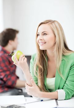 education concept - smiling student girl with green apple in college