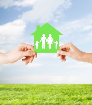 real estate and family home concept - isolated picture of male and female hands holding green paper house with family