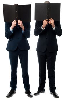 Two businessmen hiding face behind a file folder