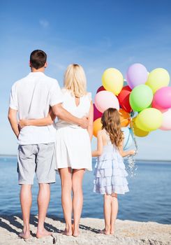 summer holidays, celebration, children and people concept - happy family at the seaside with bunch of colorful balloons