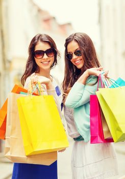 shopping and tourism concept - beautiful girls with shopping bags in ctiy