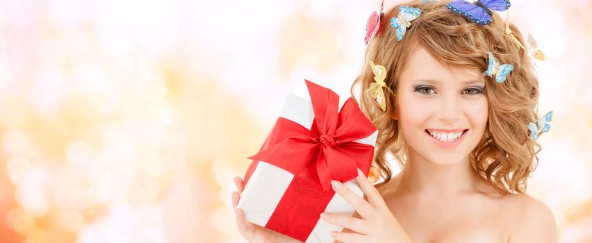 health, holidays and beauty concept - happy teenage girl with butterflies in hair showing gift box