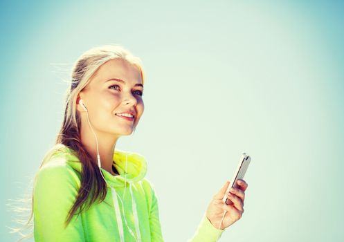 sport and lifestyle concept - woman doing sports and listening to music outdoors