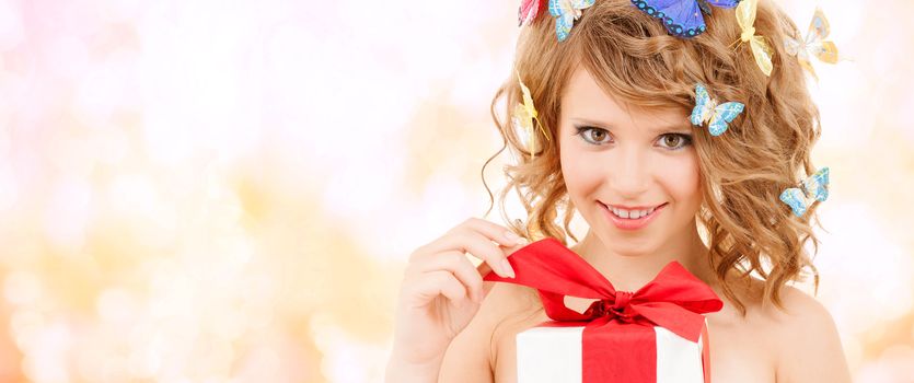 health, holidays and beauty concept - happy teenage girl with butterflies in hair opening gift box