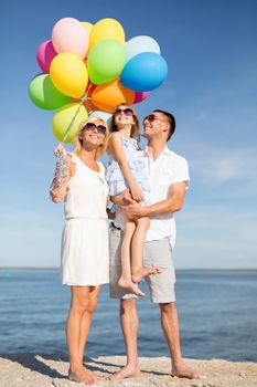 summer holidays, celebration, children and people concept - happy family with colorful balloons at seaside