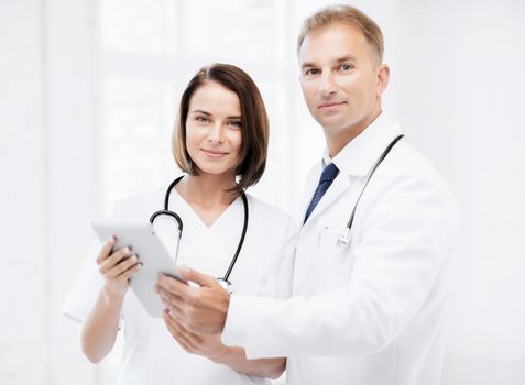 healthcare and technology concept - two doctors looking at tablet pc