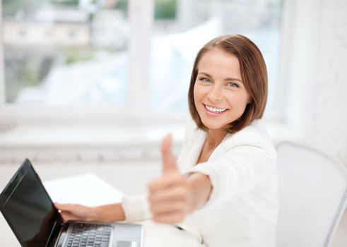 business and technology concept - businesswoman with laptop in office showing thumbs up