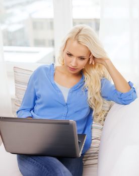 home, technology and internet concept - woman sitting on the couch with laptop computer at home