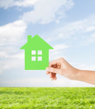 real estate and family home concept - closeup picture of female hand holding green paper house