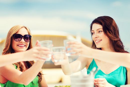 summer holidays and vacation - girls making a toast in cafe on the beach