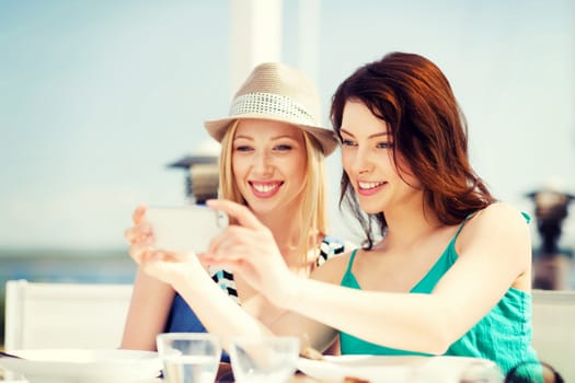 summer holidays and vacation - girls taking photo in cafe on the beach