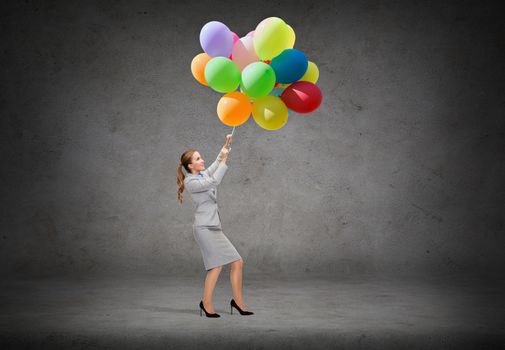 business and education concept - smiling businesswoman pulling down bunch of balloons