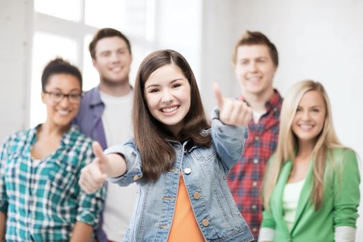 education concept - happy team of students showing thumbs up at school