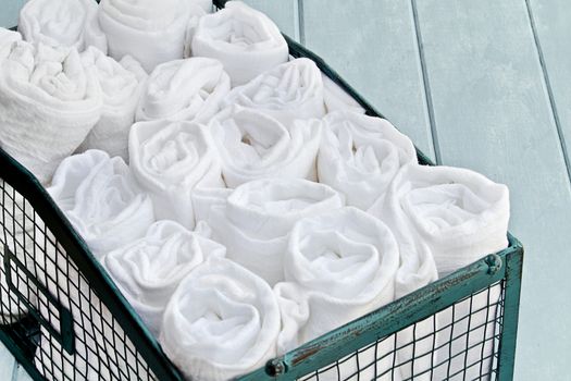 Pretty green basket filled with neatly organized rolled up cleaning rags. Shallow depth of field.