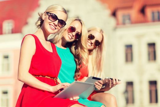 holidays and tourism concept - beautiful blonde girls toursits looking into tablet pc in the city