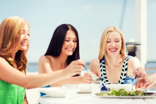 summer holidays and vacation - girls in cafe on the beach