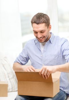 post, home and lifestyle concept - smiling man with cardboard boxes at home