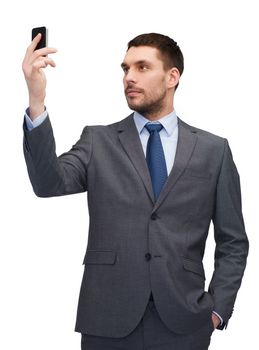 business, technology, internet and education concept - friendly young businessman with smartphone