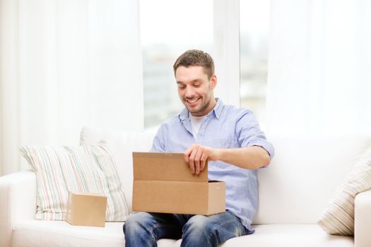 post, home and lifestyle concept - smiling man with cardboard boxes at home