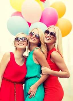 holidays and tourism, friends, hen party, blonde girls concept - three beautiful women with colorful balloons in the city