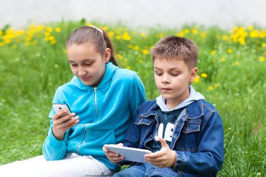 two children with gadgets outdoors