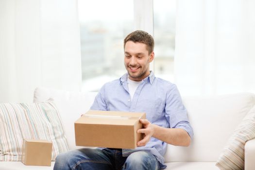 post, home and lifestyle concept - smiling man with cardboard boxes at home