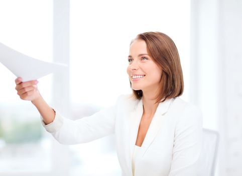 business and education concept - smiling businesswoman giving papers in office