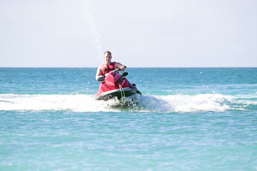 Young guy cruising on a jetski on the caribbean sea