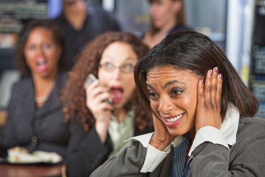 Pretty business woman covering ears while person talks on phone