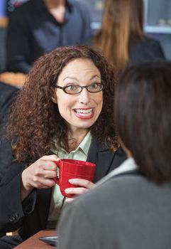 Happy business woman with red mug talking to friend