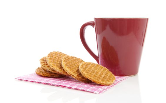 Pile of typical Dutch stroopwafels ( with syrup) on napkin near coffee cup over white background