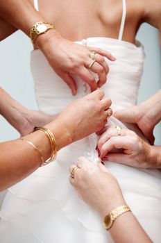 Woman hands helping to place the bride dress. Button from behind.