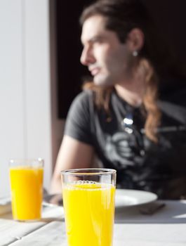 Boy having breakfast glass of orange juice in the light of a window