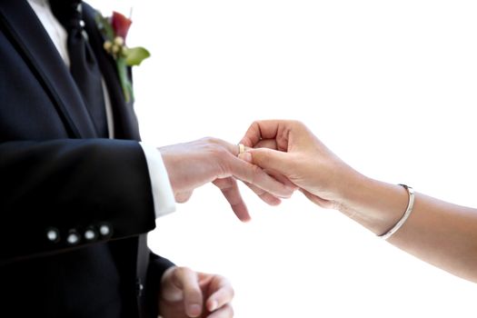 Close-up of newlywed couple putting wedding ring on the finger with white background