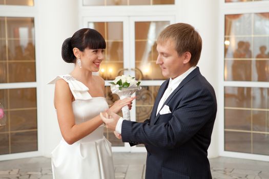 groom putting on a wedding ring to a bride