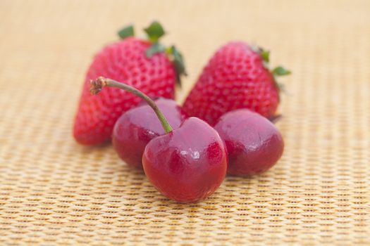 strawberries and cherries on wicker mat