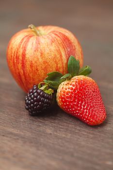 juicy apple,blackberry and strawberry on a wooden surface