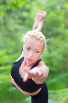 Young caucasian lady is practicing yoga in the nature.